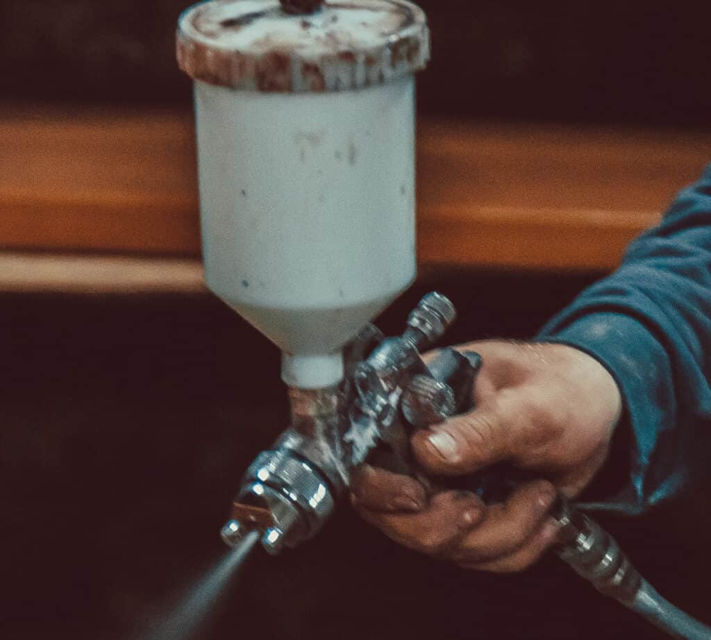 man holding spray paint gun, while spraying paint